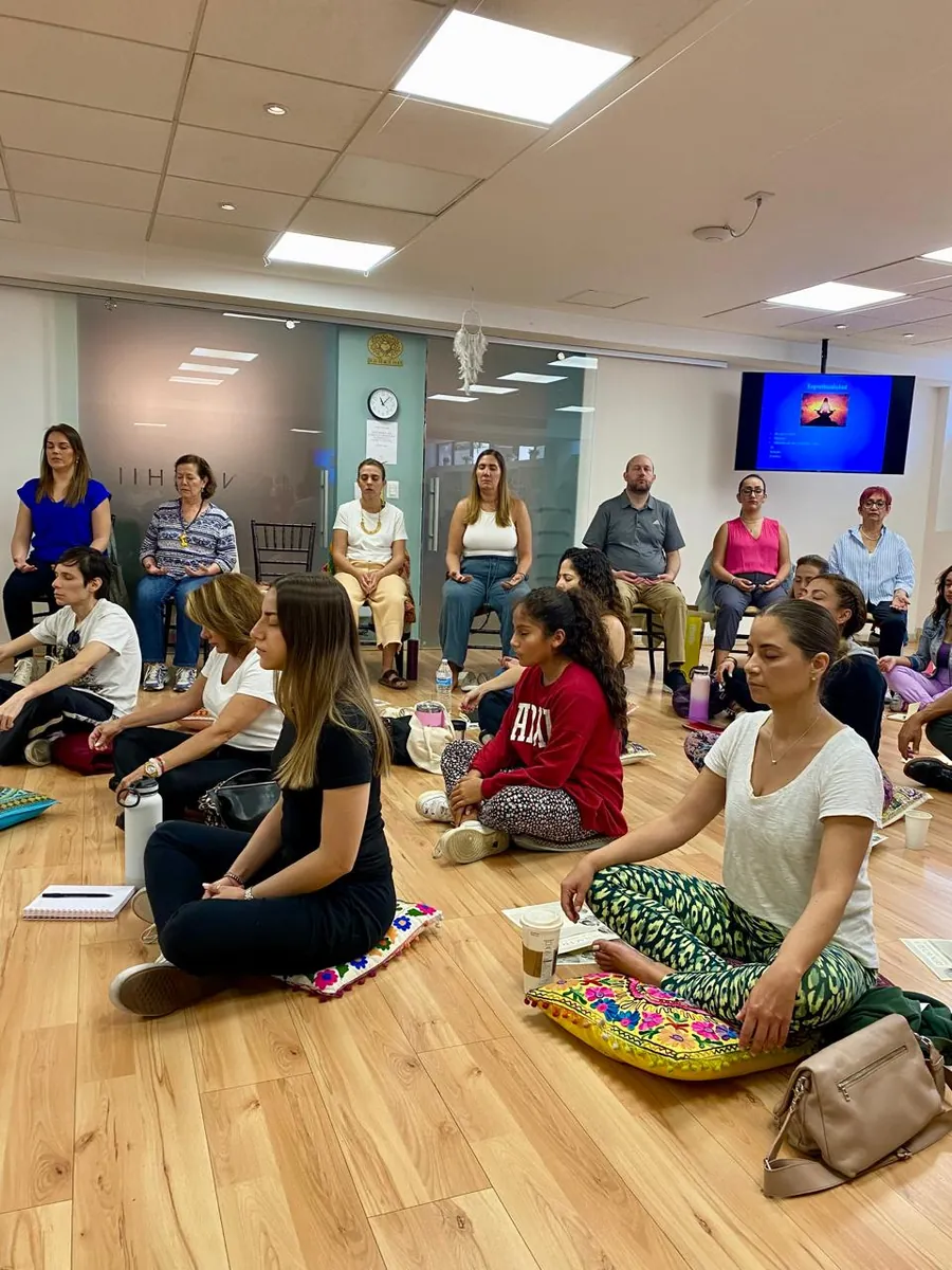 Participantes sentados en círculo en el piso durante una meditación